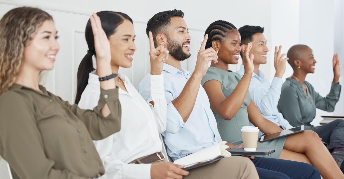 A group of people raise their hands to participate in a survey